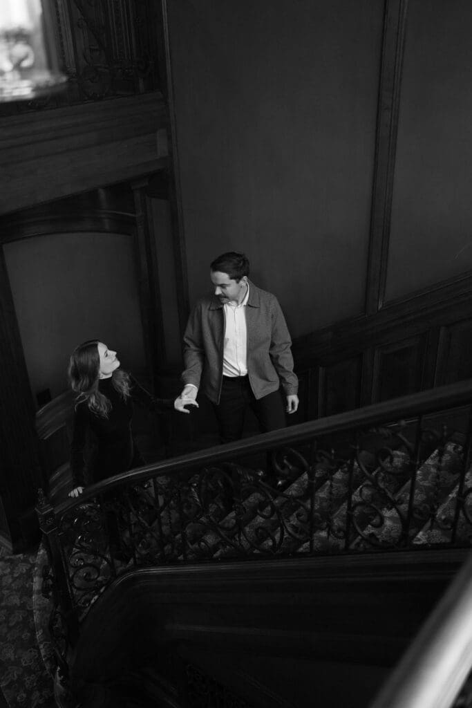 A black and white photo of a man leading a woman upstairs