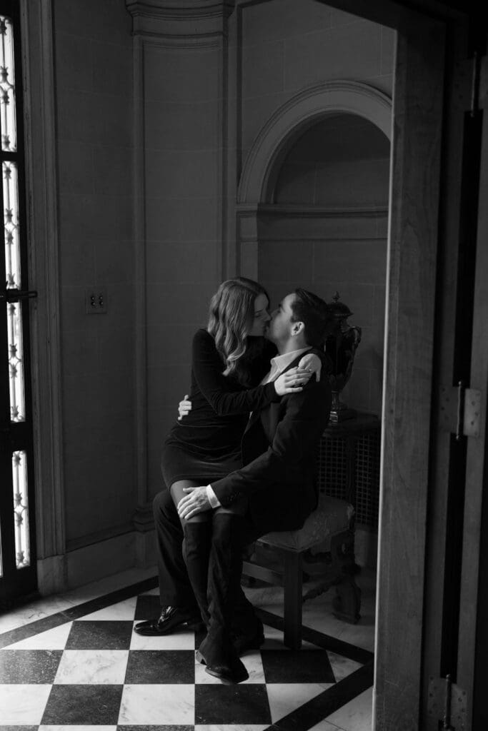 black and white photo of a man and woman kissing inside a corridor