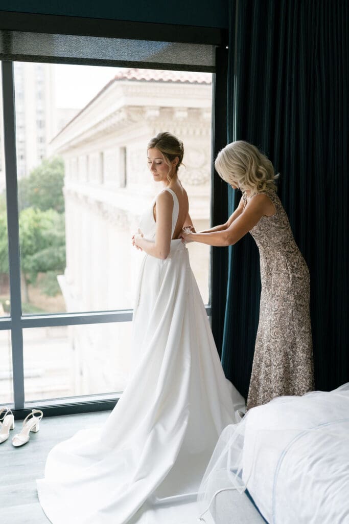 bride getting dressed with mother